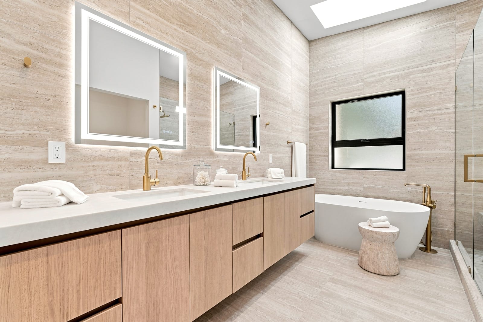 Travertine bath with a floating vanity and a freestanding tub