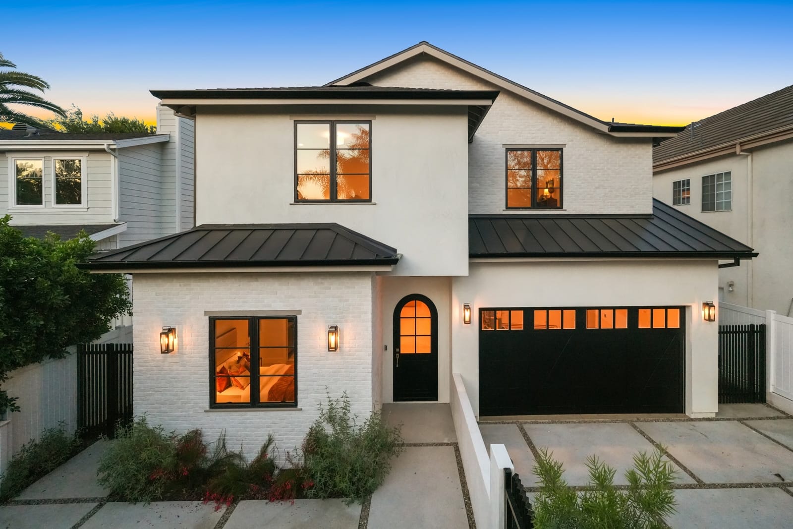 Two-story new build at twilight, windows and lanterns lit