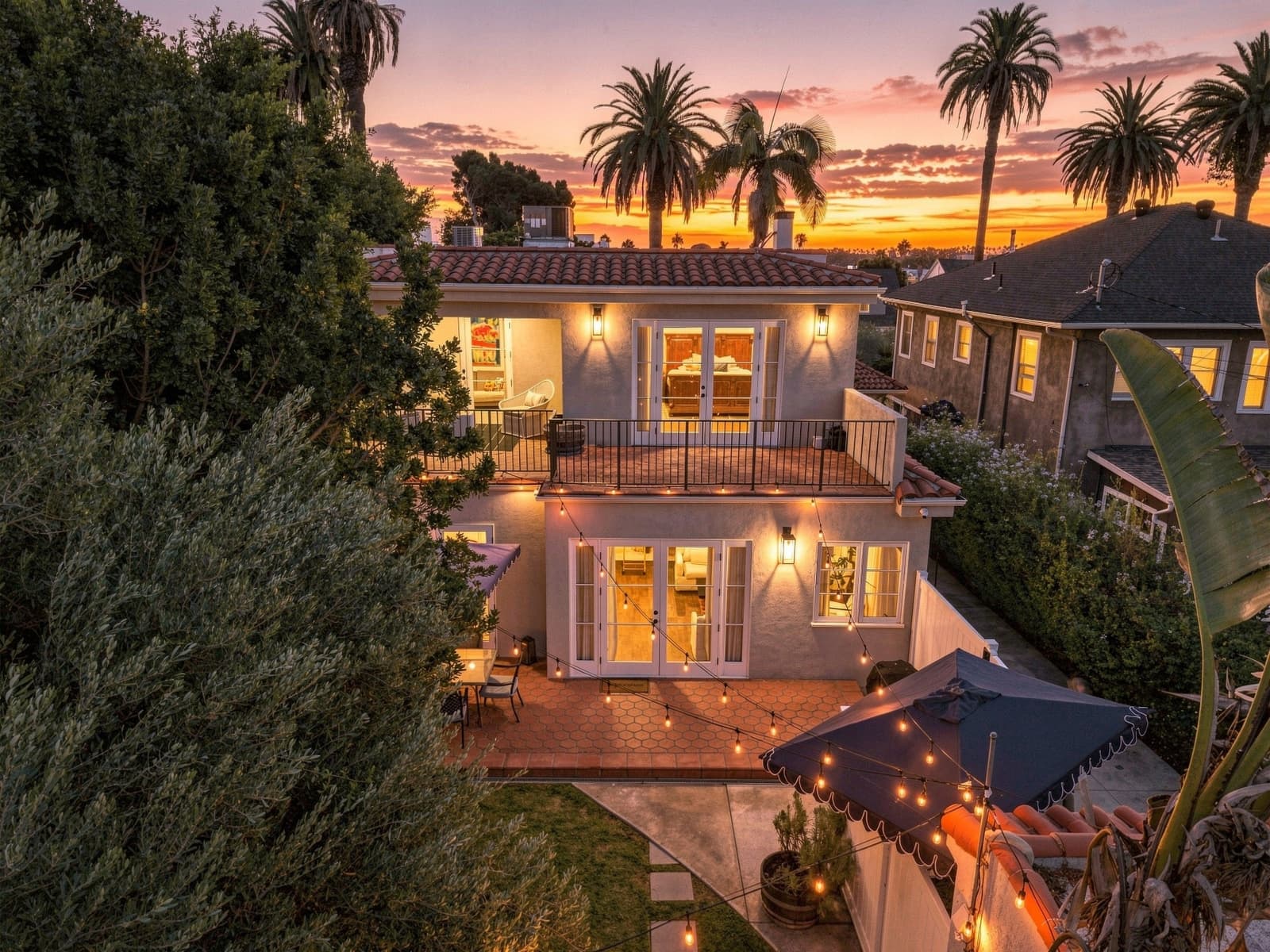 A drone frame past a Spanish two-story balcony at sunset.
