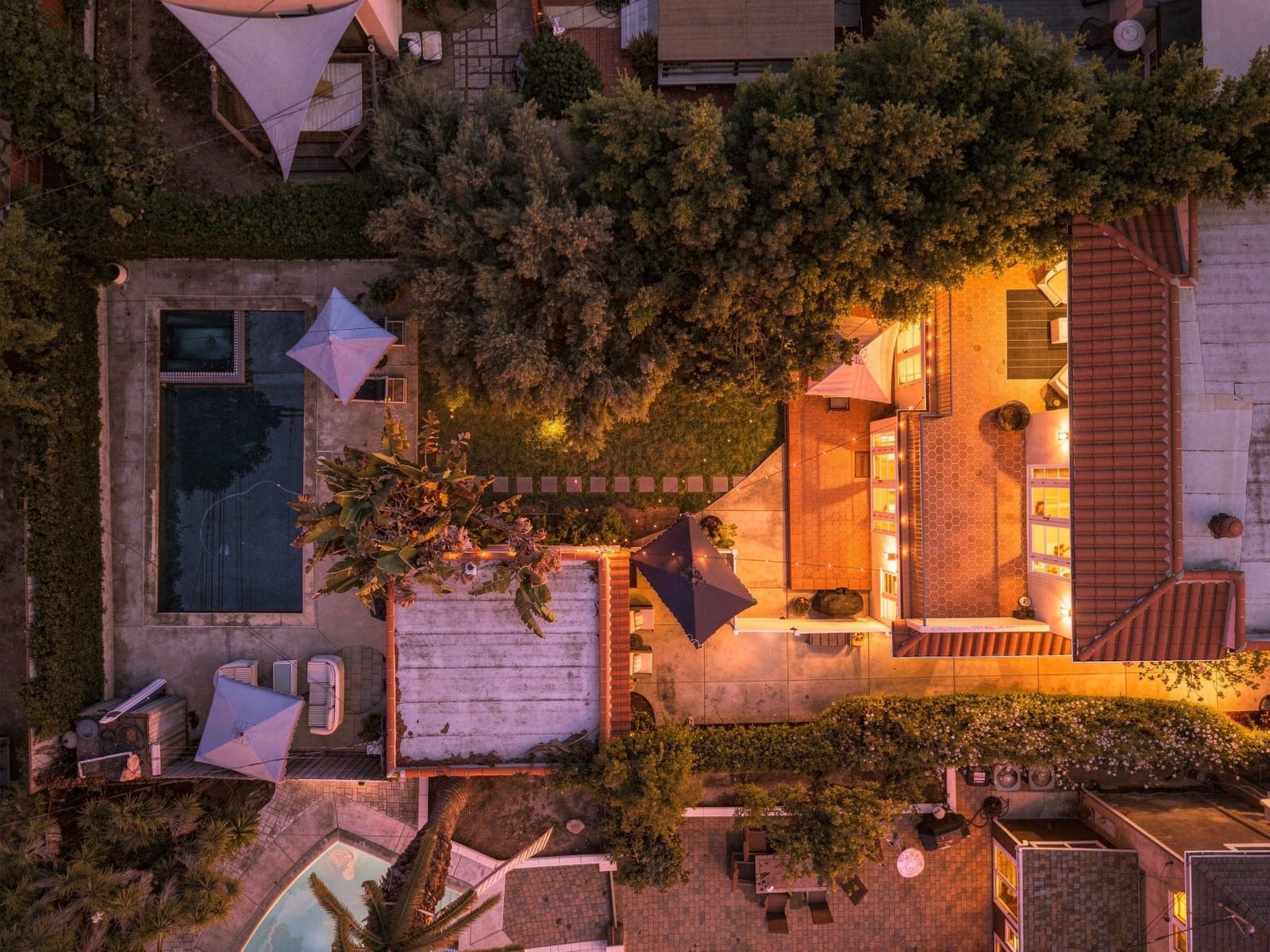 A drone frame looking straight down on a lit pool at twilight.