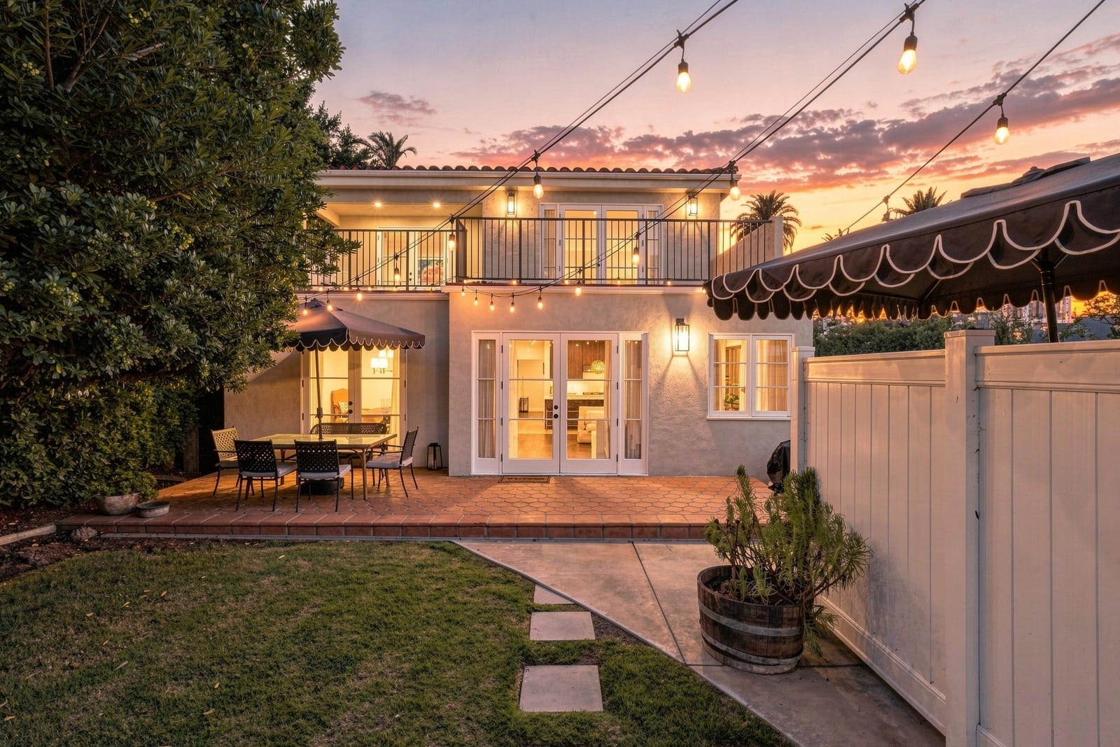 Rear of a Spanish two-story at twilight, string lights over the lawn