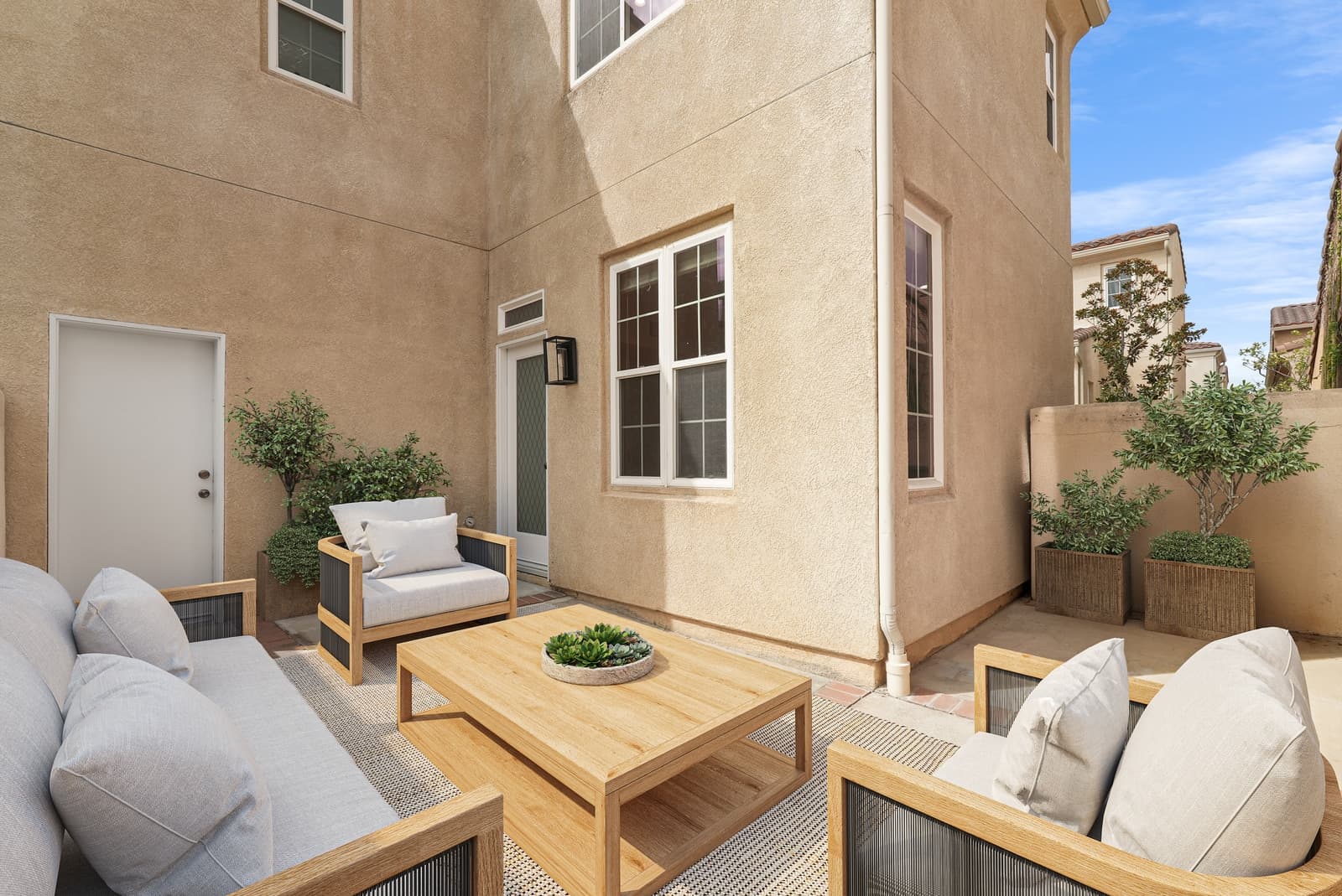 The same courtyard, virtually staged with an outdoor sofa, chairs and planters