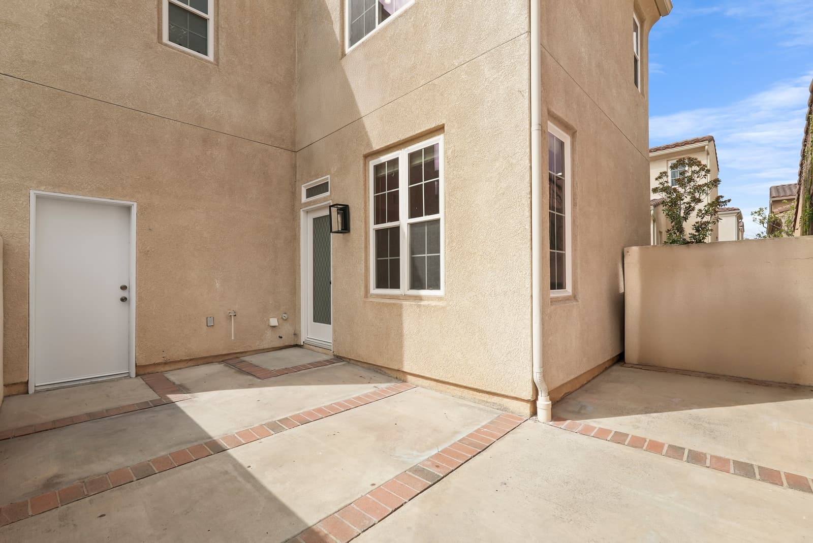 Empty side courtyard with a paved patio and a low stucco wall