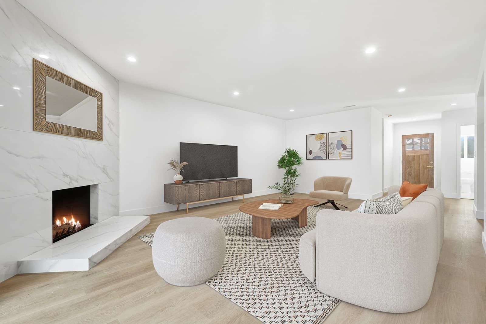 The same living room virtually staged with a curved cream sofa, a round upholstered pouf, a wood coffee table, a low media console and a patterned rug