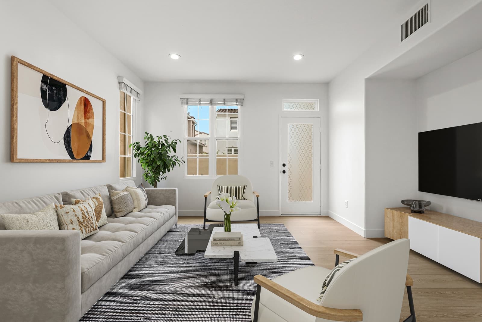 The same great room, virtually staged with a sofa, a TV console and art