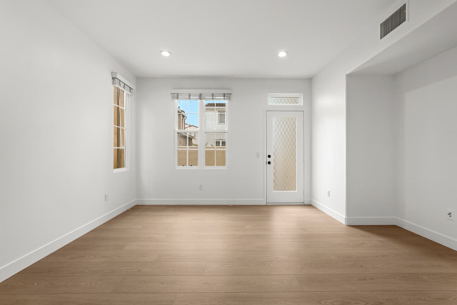 Empty great room with a door to the patio and tall windows