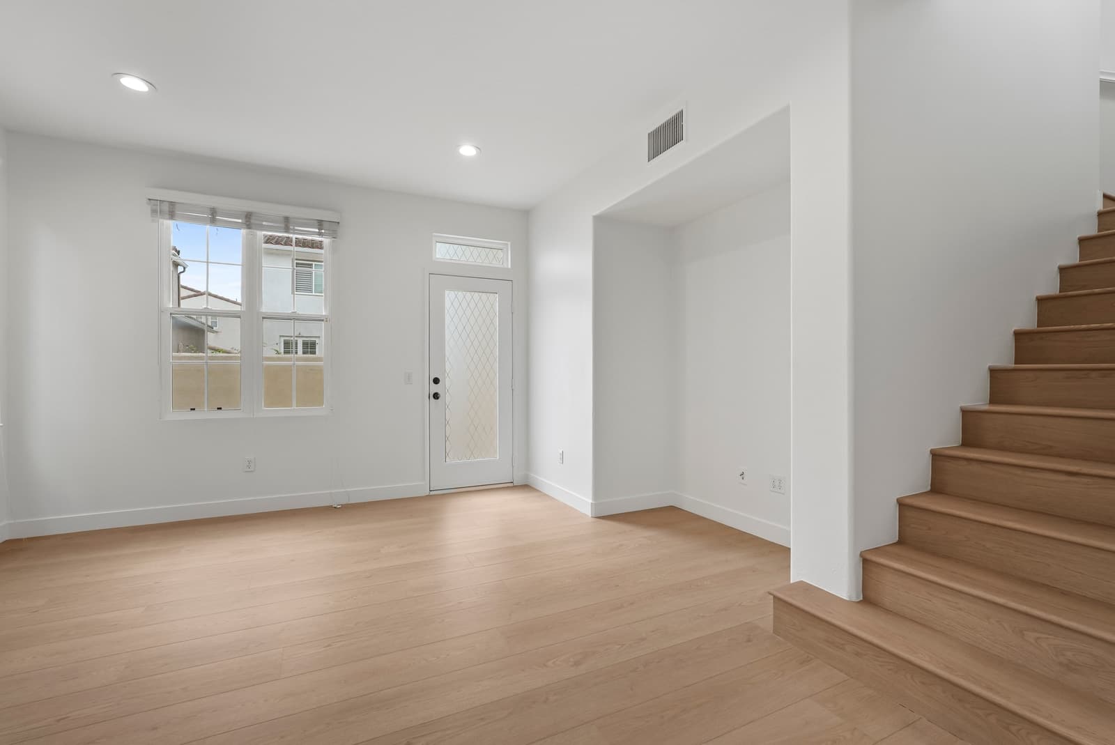 Empty living room with a staircase and a door to the yard, new construction