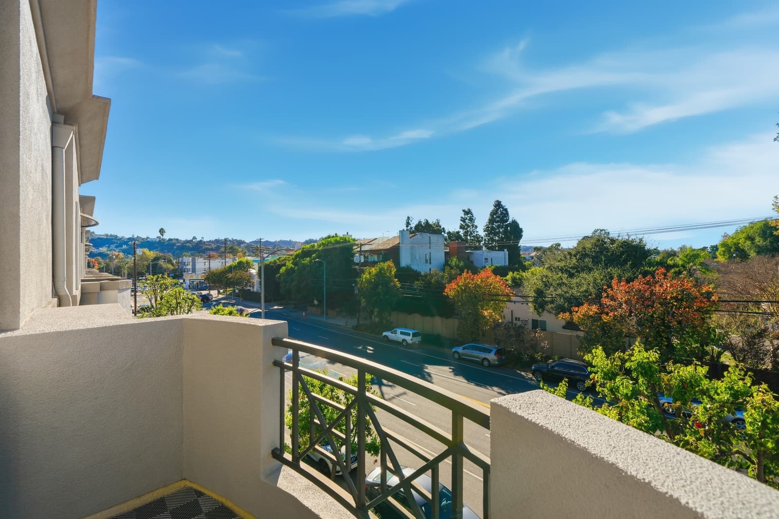 Condo balcony looking out over a tree-lined boulevard toward the hills, photographed by VVT in Studio City