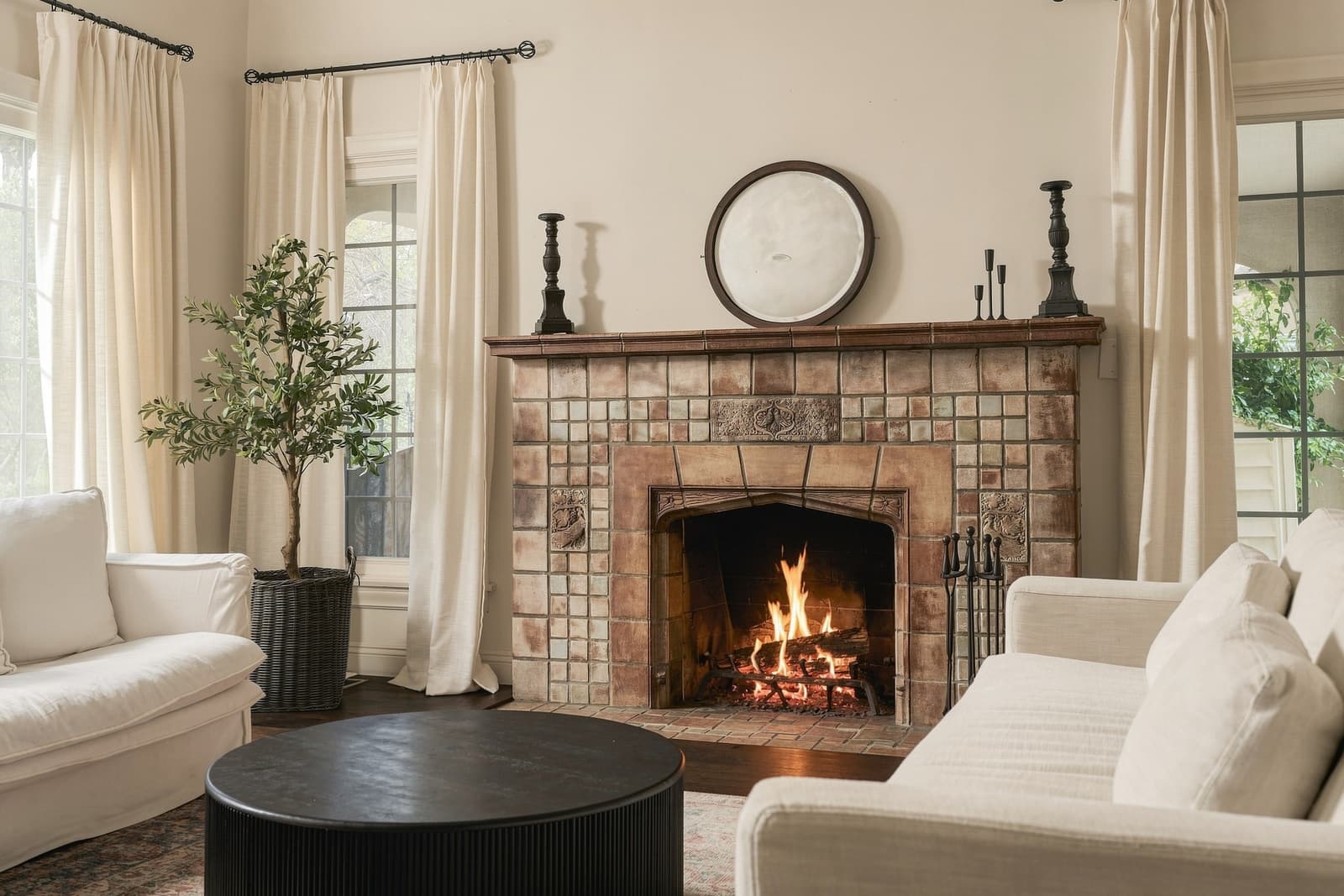 Tile fireplace lit under a round mirror