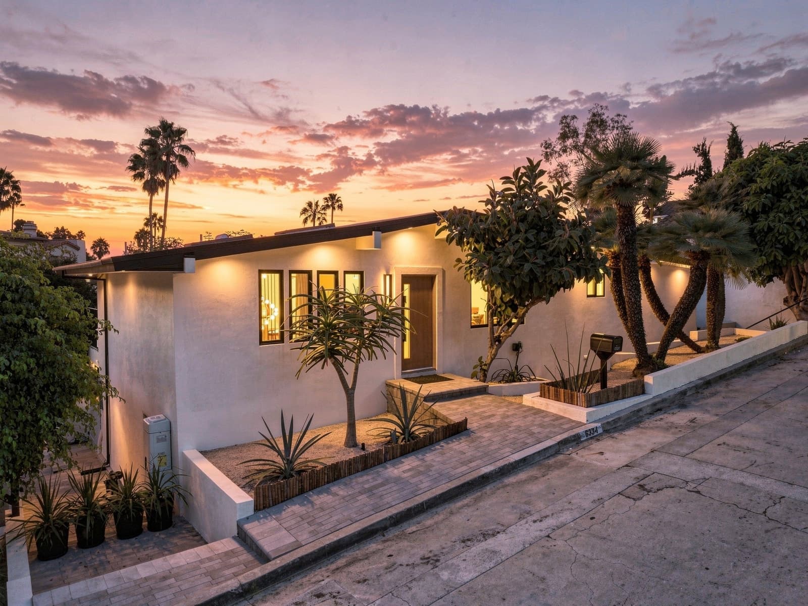 Front entry with palms and agaves at twilight, the windows lit