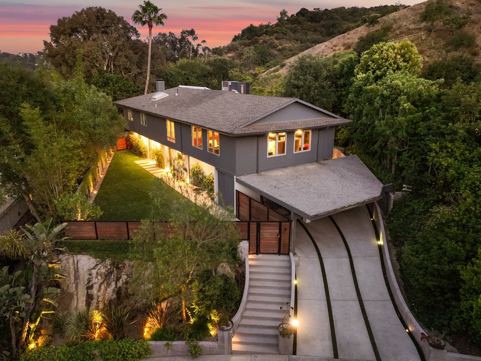 Hillside home at twilight with a winding driveway, from above