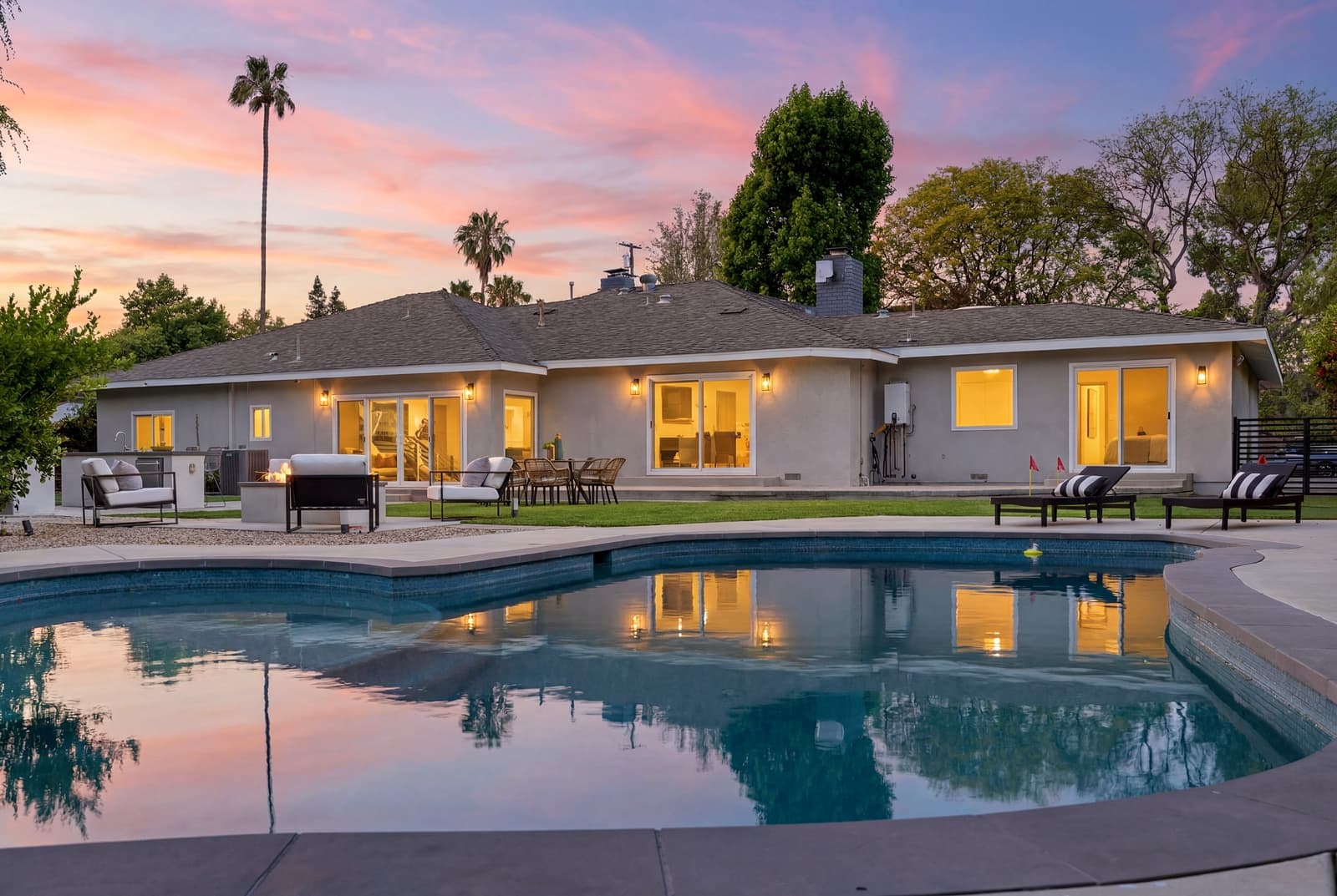 Ranch home and pool at twilight, framed by palms