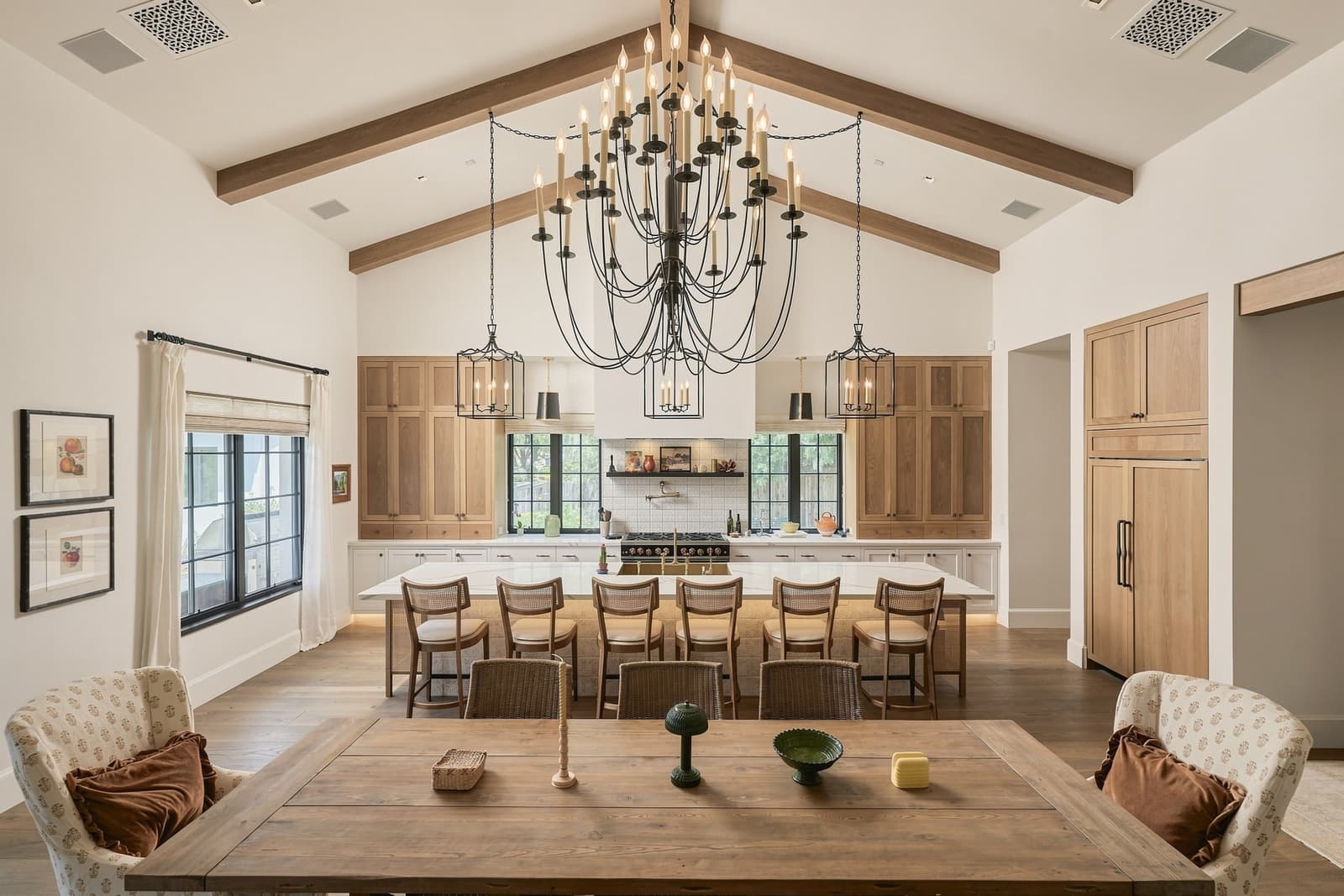Vaulted kitchen with an oak island and chandeliers over the dining table