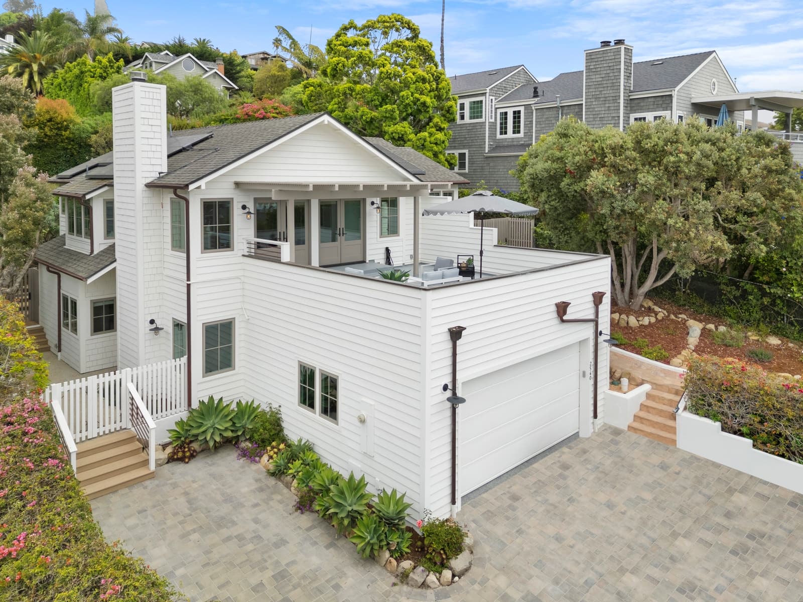 Drone view of a white coastal farmhouse with a roof deck, shot in daylight