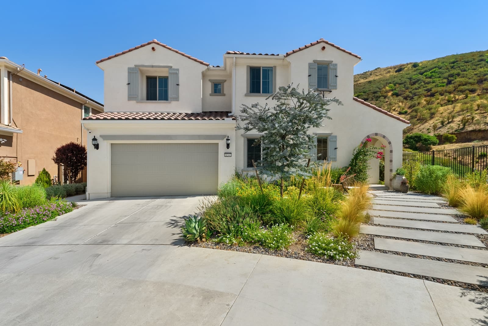 Spanish-style two-story with a tile roof and a paver drive, shot in daylight