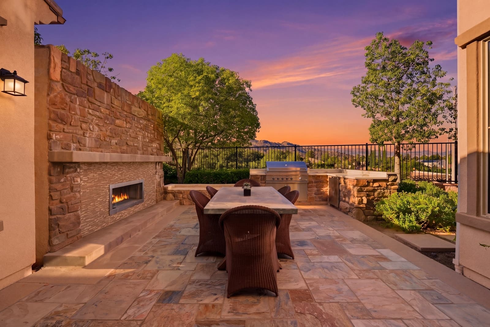 Stone outdoor fireplace and dining patio at twilight, West Hills