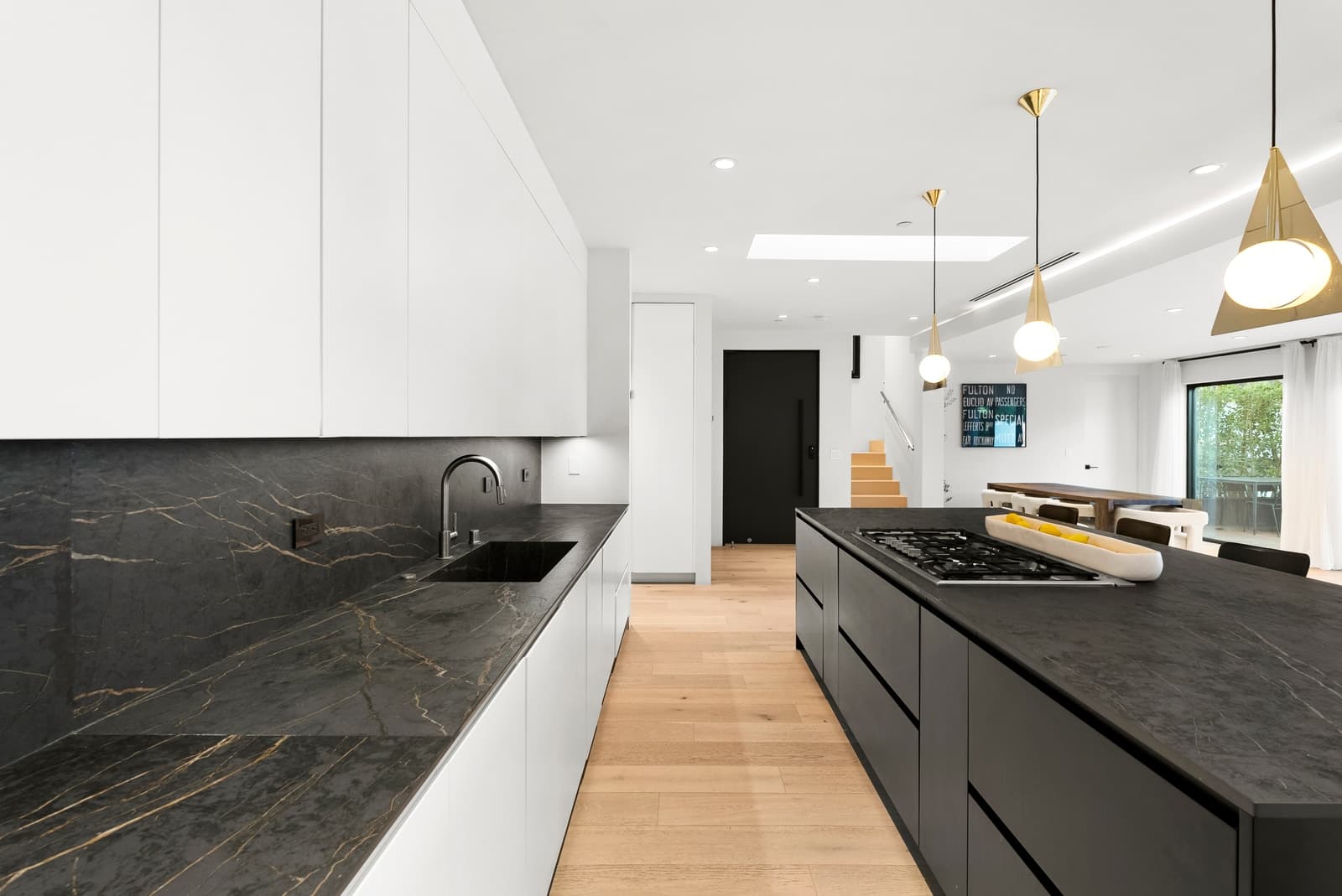 Black kitchen with a long island and a glass wall to the courtyard