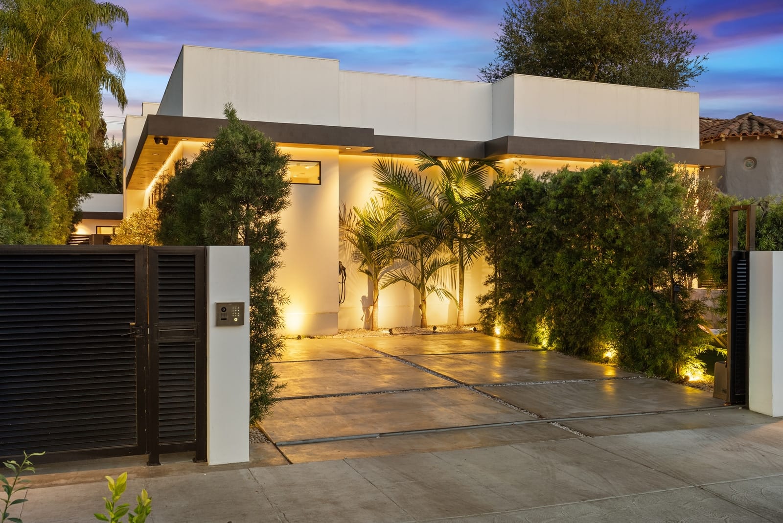 Gated modern at twilight, the courtyard lit behind the gate