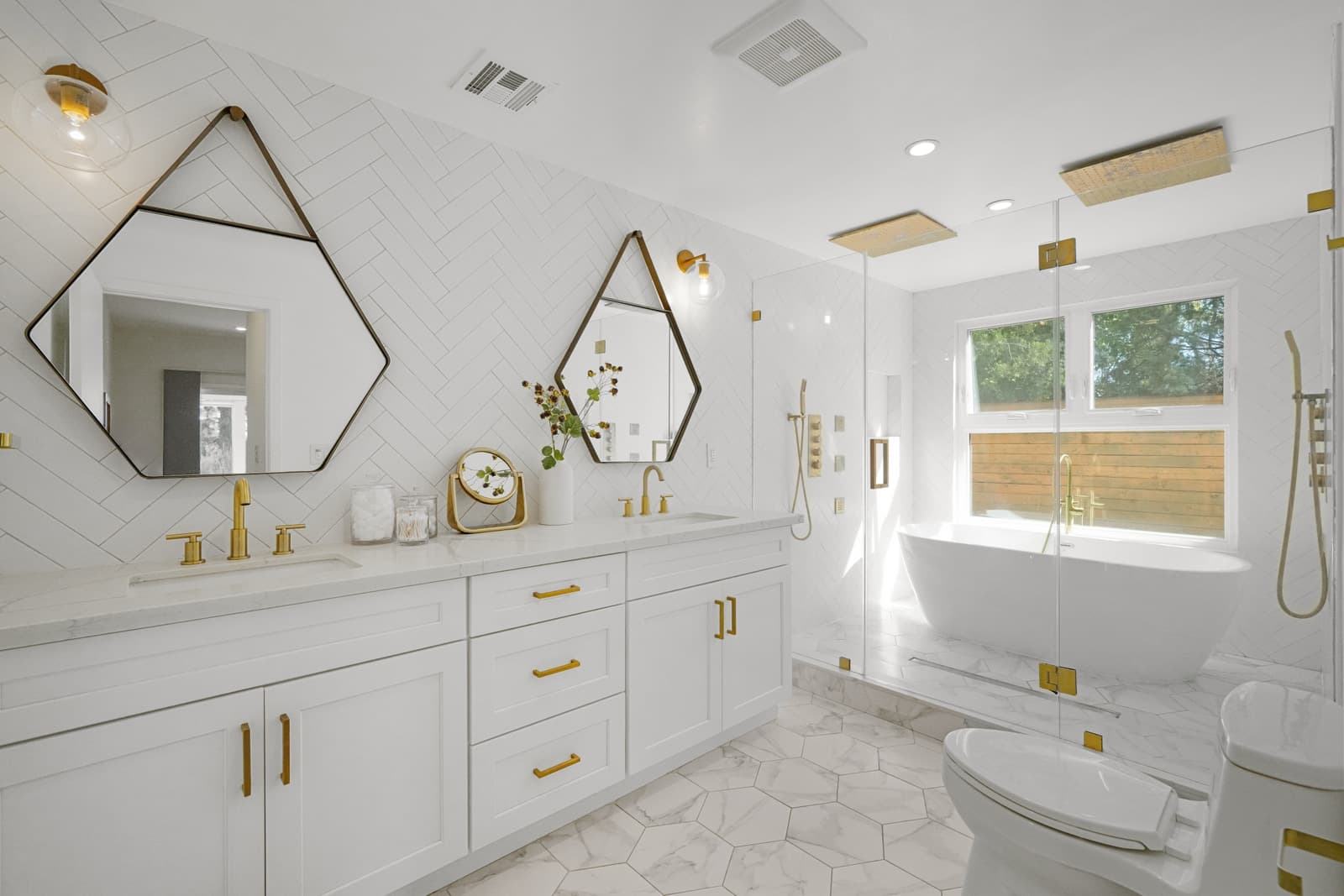 White bathroom with hexagonal mirrors and brass hardware