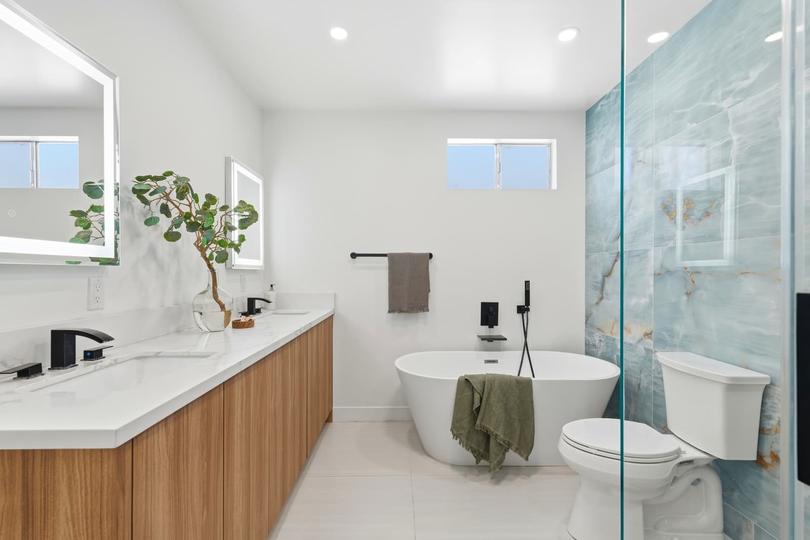 White bathroom with an oak vanity and a glass shower