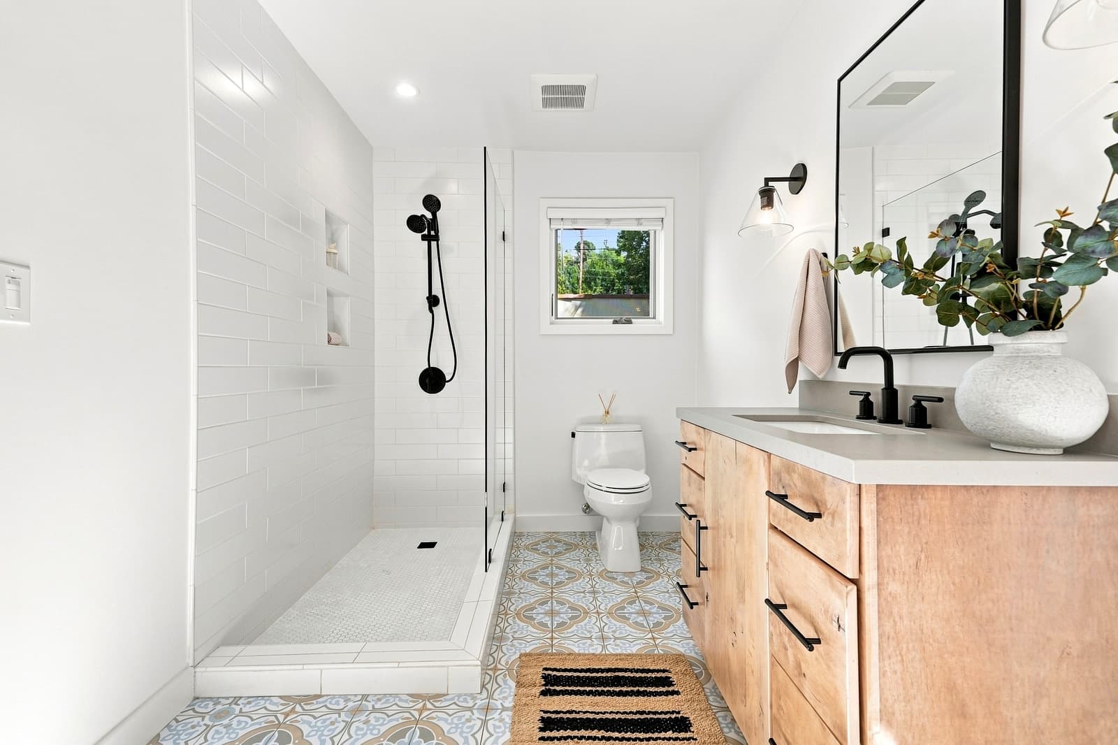 White bath with a walnut vanity and patterned floor