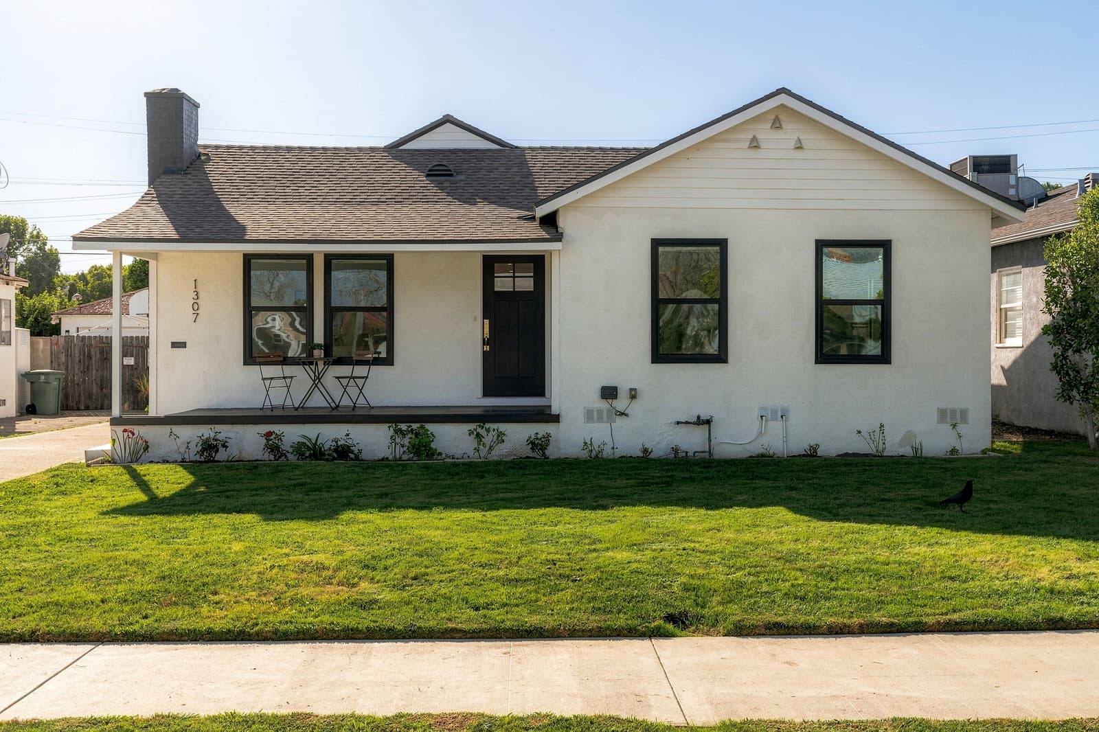 White bungalow with a black door and a wide front lawn