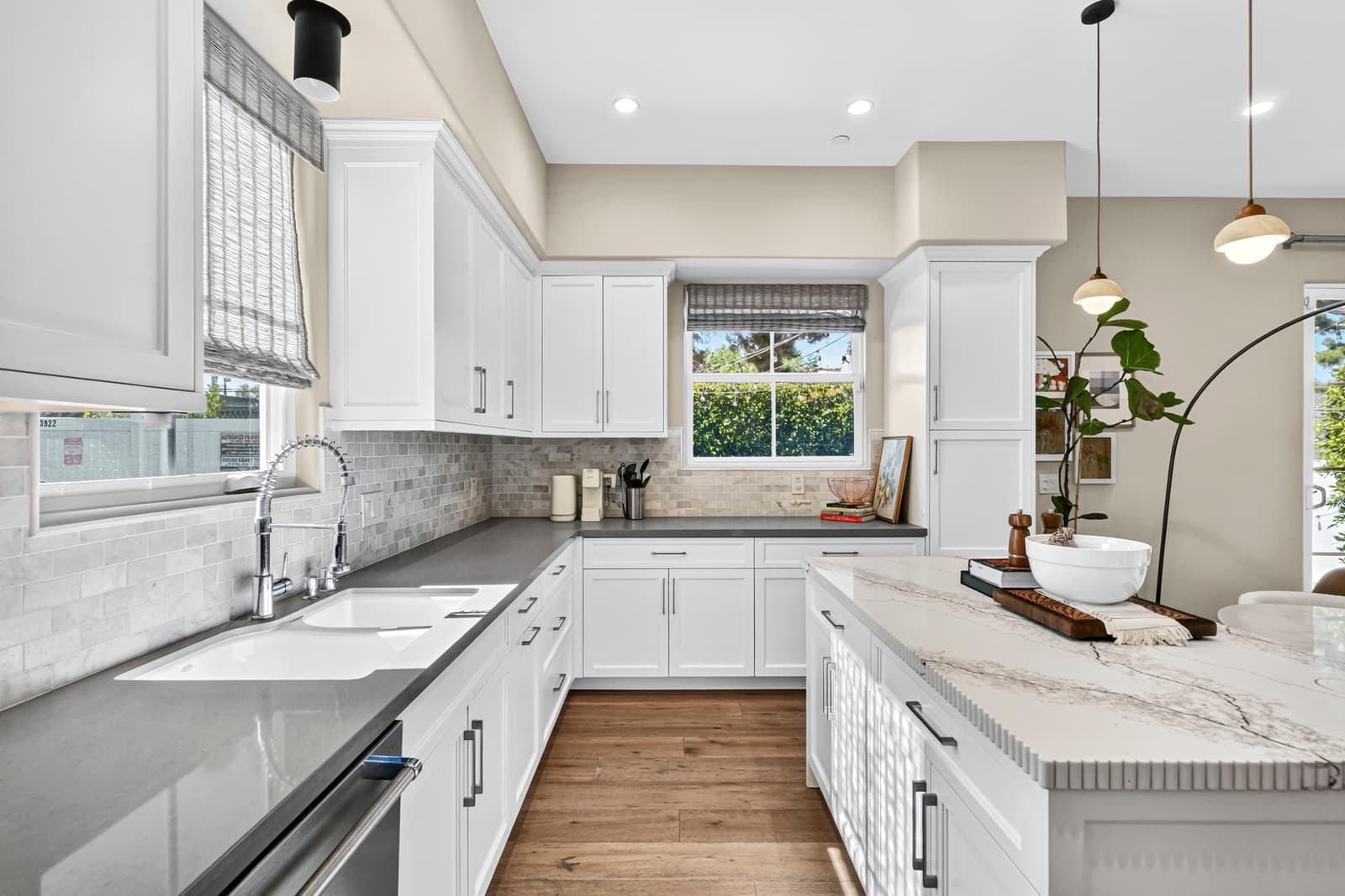 White kitchen with a deep farm sink, grey counters and a marble tile backsplash