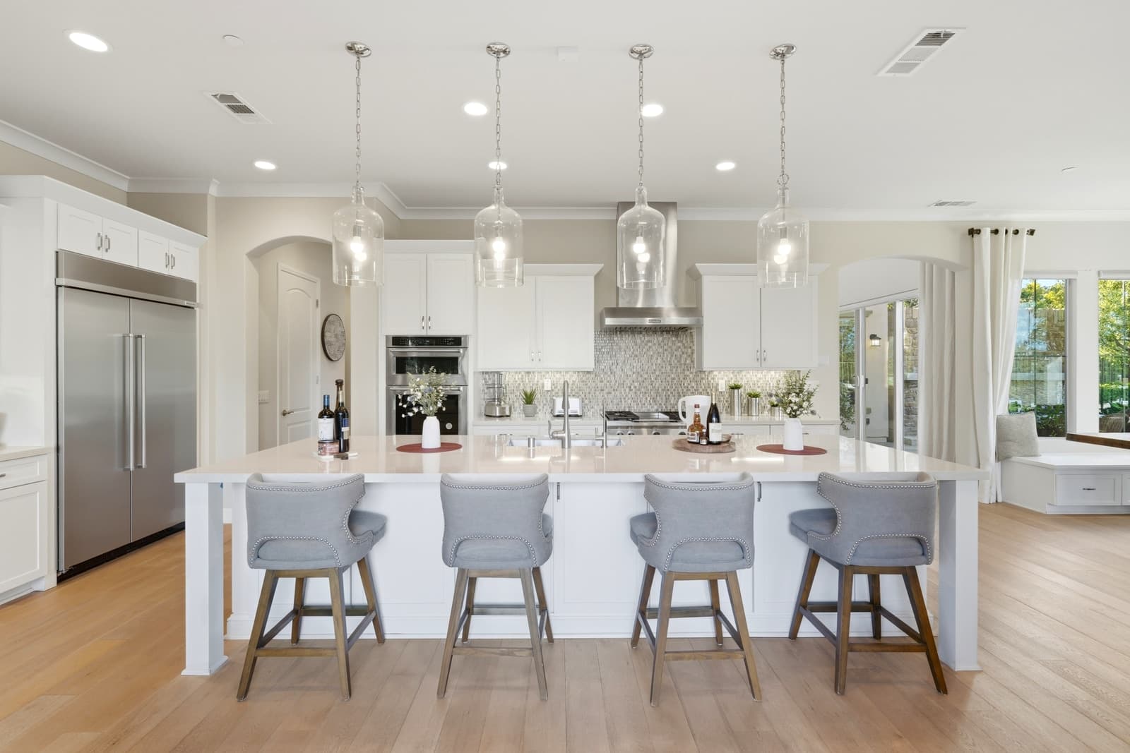 White kitchen island with glass pendants and grey stools