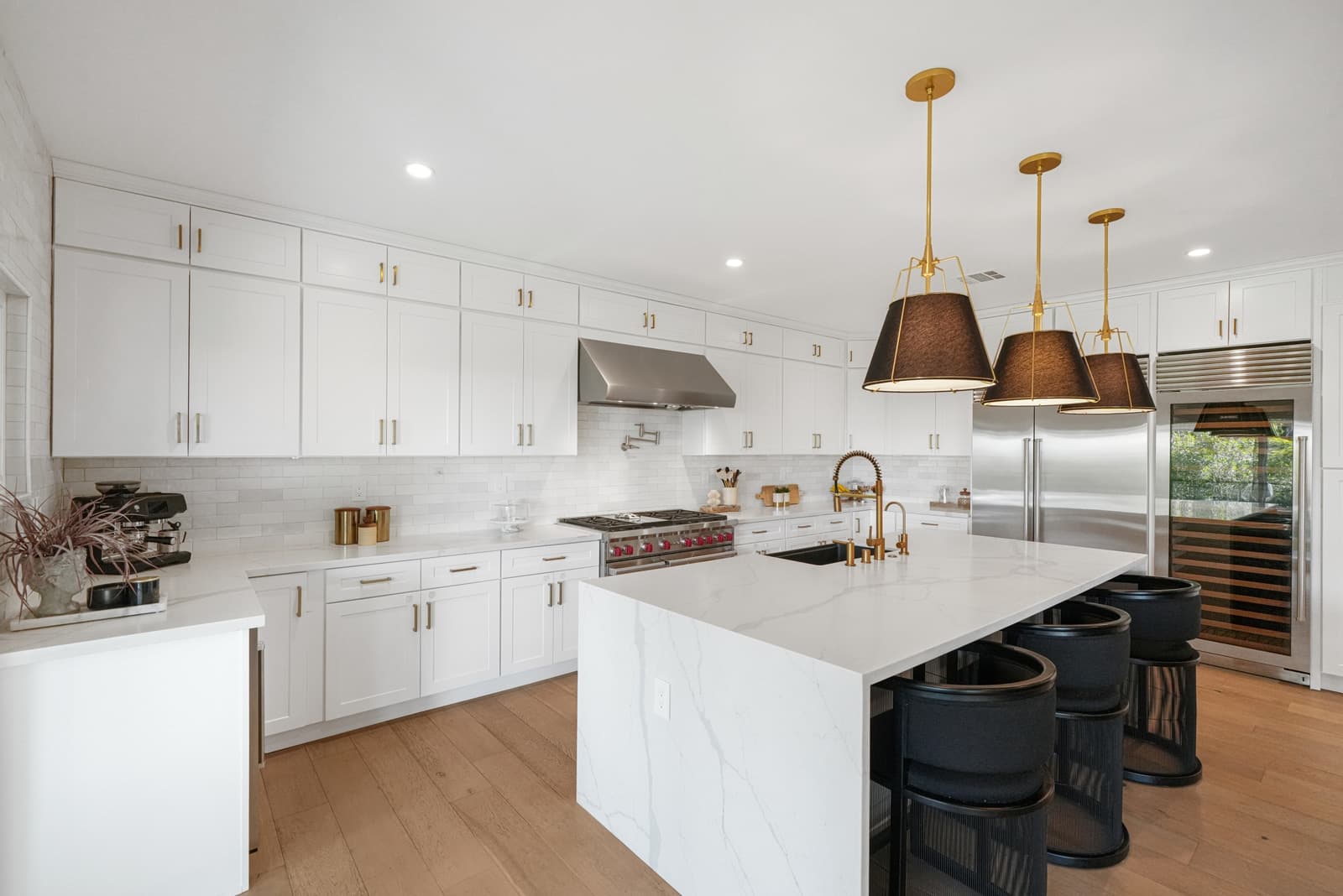 White kitchen with a marble island and black leather stools