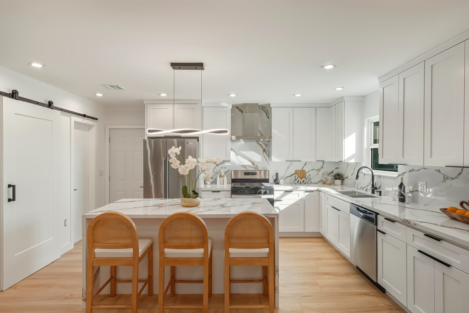 White kitchen with a marble island and counter stools