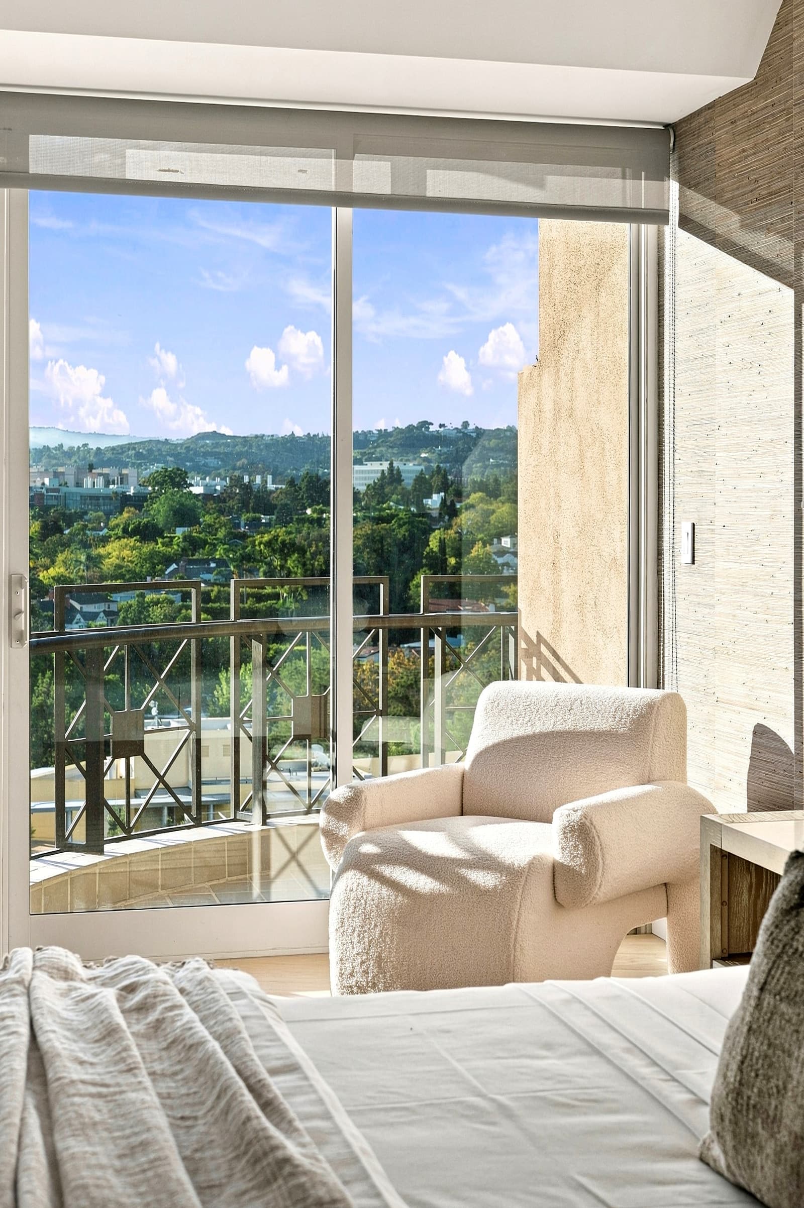Bedroom armchair beside the balcony doors, treetops beyond