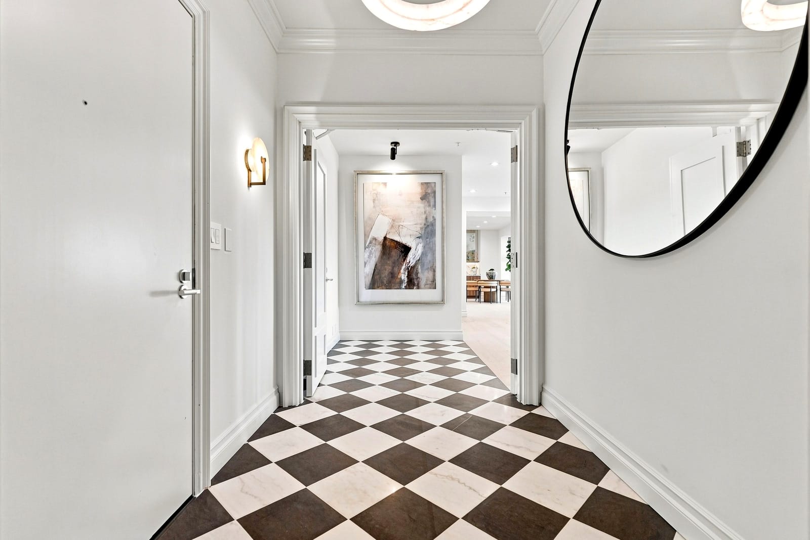 Entry hall with a checkerboard stone floor and a round mirror