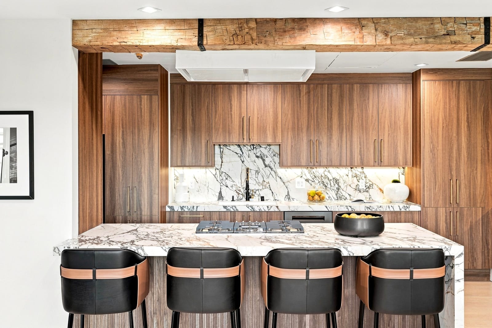 Walnut kitchen with a marble island and leather stools, seen straight on