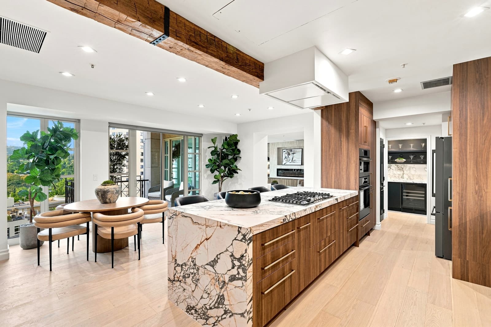 Walnut kitchen with a marble island, dining table by the window beyond