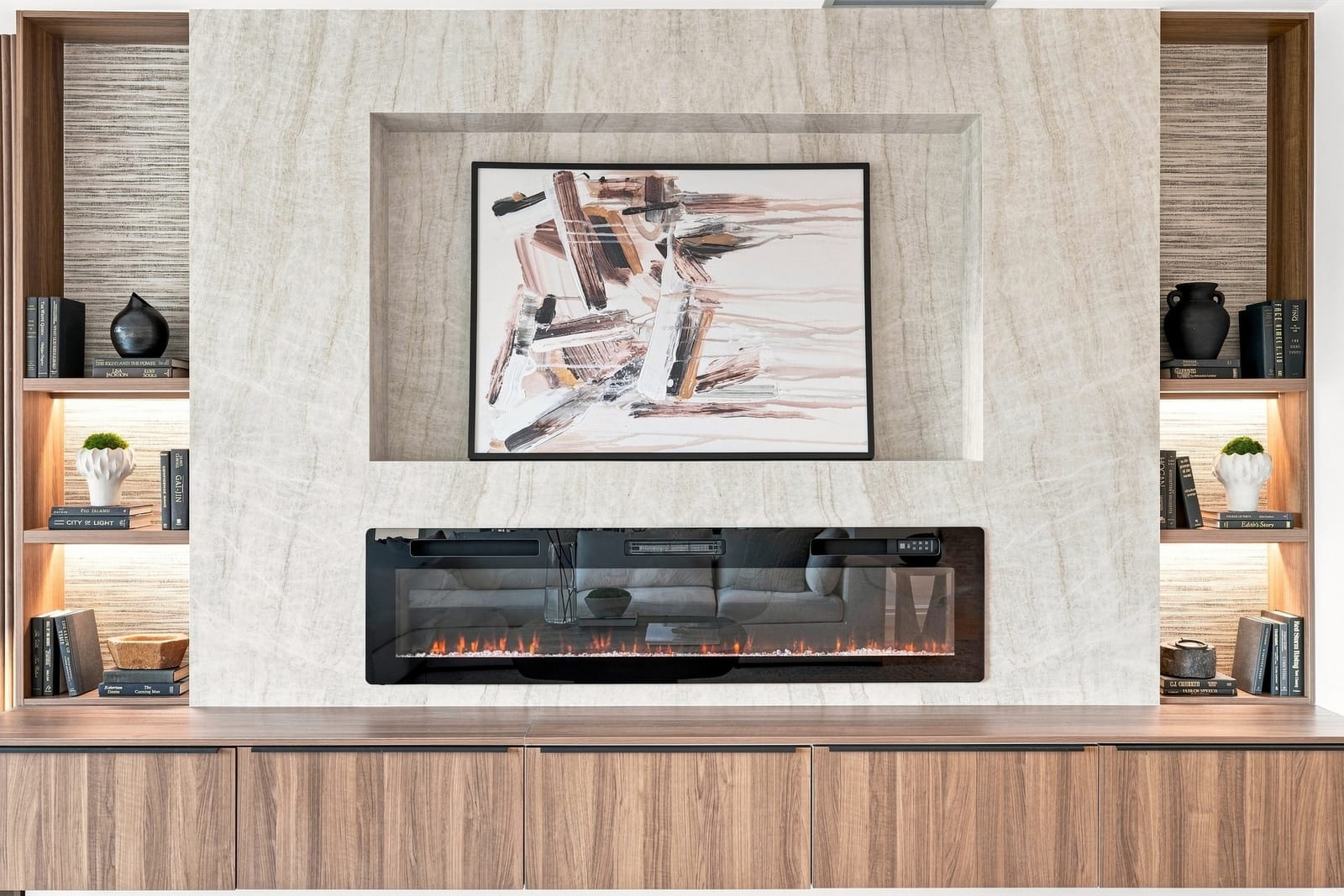 Travertine fireplace wall with a linear fire and lit shelving, seen straight on