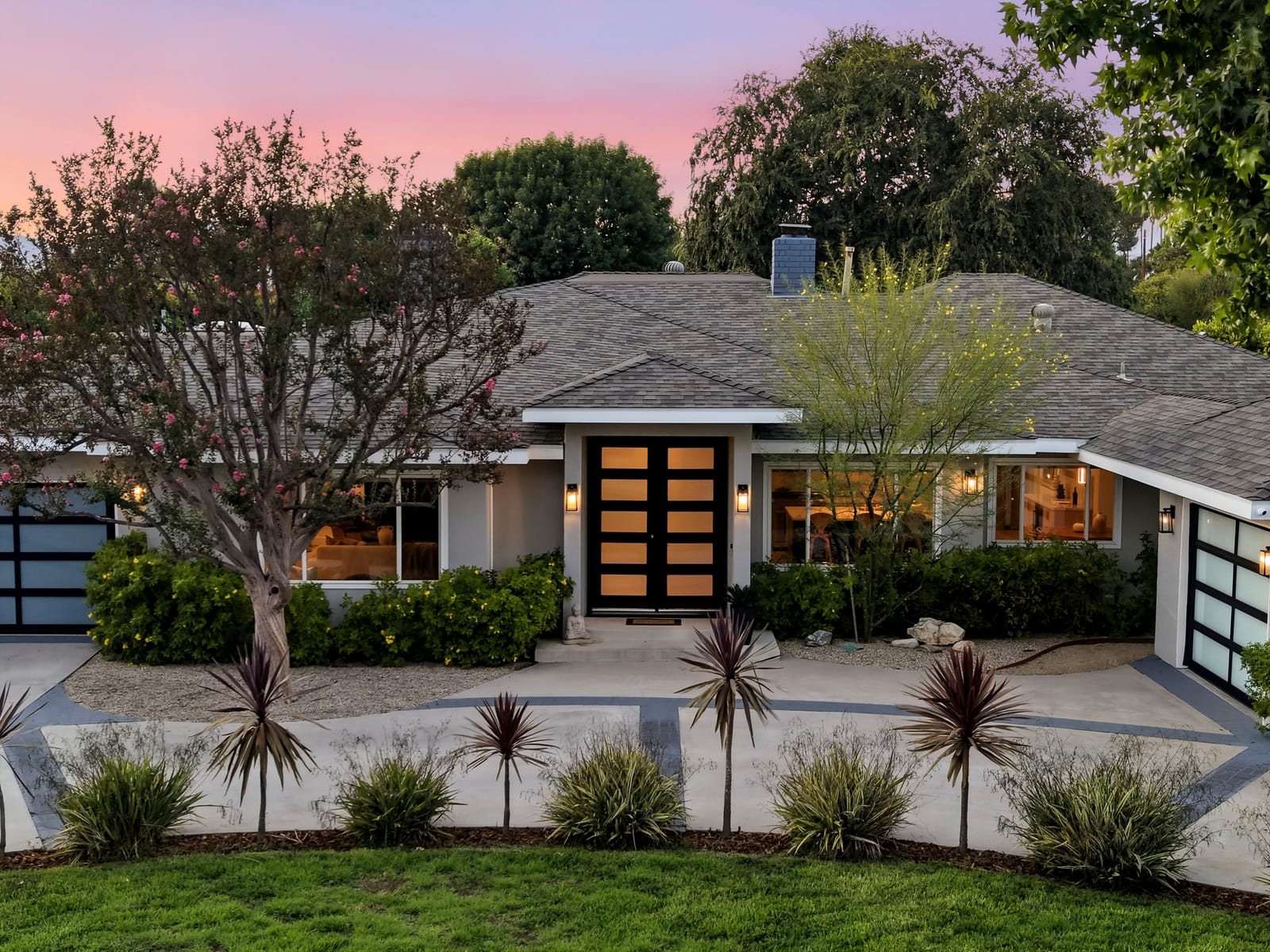 Front of a single-story at twilight, black double doors lit