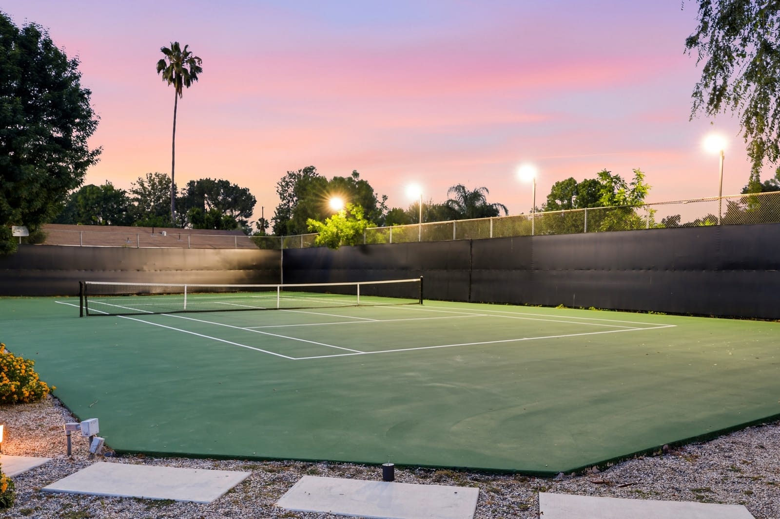 Private tennis court under its lights at dusk