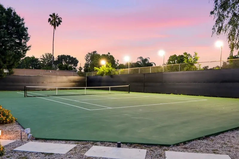Backyard tennis court lit at dusk with palms and a pink sky, Woodland Hills
